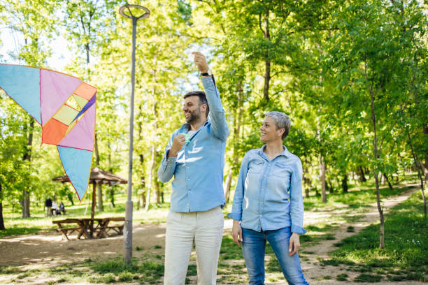 istock Happy couple having fun in the park, launching a kite 1318449470