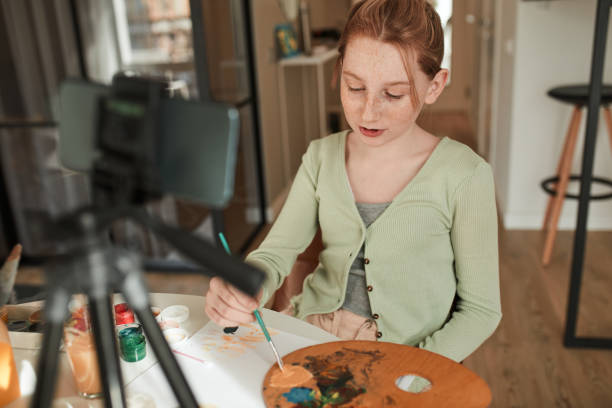 istock Ginger girl drawing with acrylic paints while broadcasting for her blog about art 1318450532