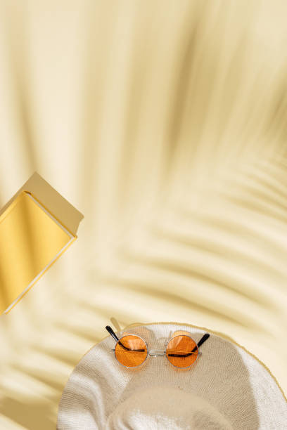 istock Summer beach rest concept background with sun hat, colored sunglasses, book with palm tree shadows 1318451857