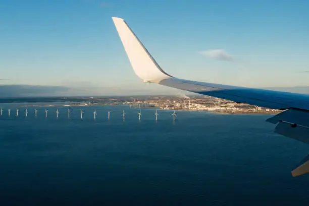 A Boeing 737 of Ryanair low cost company landing at Copenhagen Kastrup airport. View of the North Sea cost of Copenhagen and wind turbines.