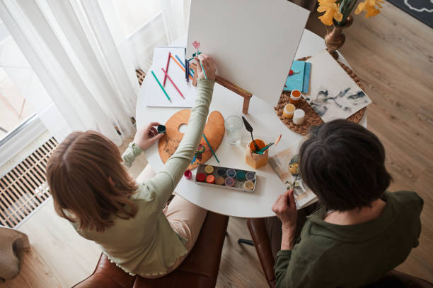 istock Kid creating with paints while her grandmother sitting near and drawing 1318453288