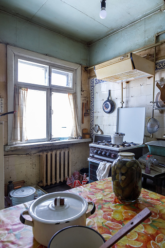 The interior of the old dirty kitchen with outdated furniture and household items