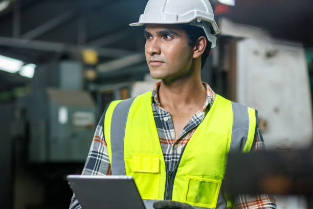 istock Male technician who wearing safety uniform is using the tablet while he is checking the machine or production process. 1318454321