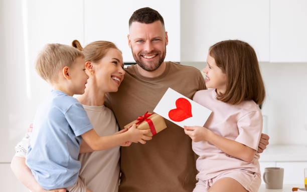 istock Mother and two smiling kids congratulating dad with Fathers day while standing in kitchen in morning 1318455199