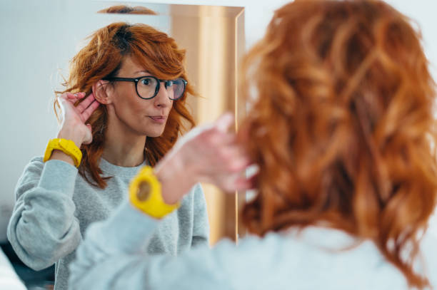 istock Young redhead woman putting a hearing aid in her ear 1318457586