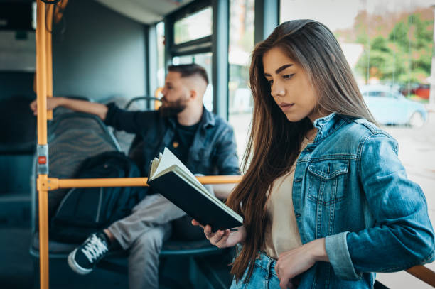 istock Woman reading a book while standing in a moving bus 1318457617