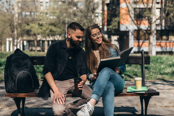 istock Two students sitting on a bench in a campus and studying for their exam 1318457624