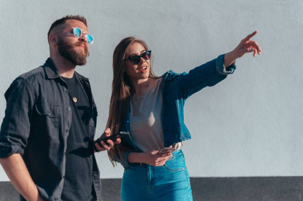 istock Couple using smartphones while standing in front of a white wall 1318457636
