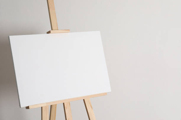 istock Wooden easel with blank canvas on light background. Space for text 1318458503