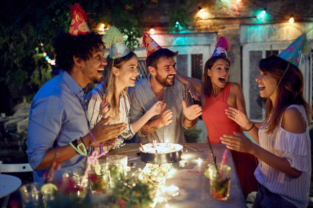 a group of cheerful friends celebrating a birthday at the open air party. quality friendship time together - city night lighting equipment mid air imagens e fotografias de stock