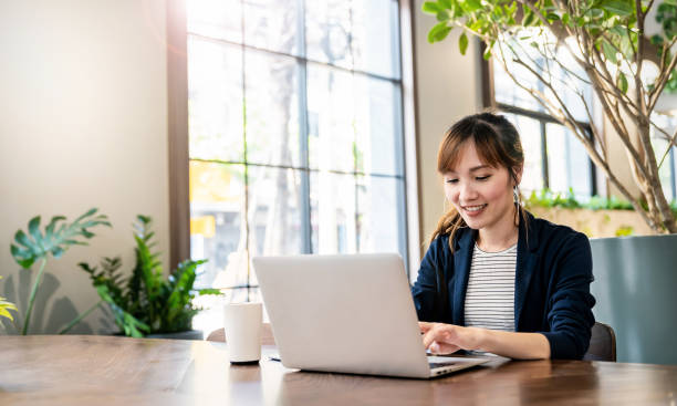 肖像微笑美麗的商業亞洲女人在辦公室辦公桌虛擬電腦工作的粉紅色西裝。小企業主員工自由職業者在線sme行銷電子商務電話行銷概念 - laptop 個照片及圖片檔