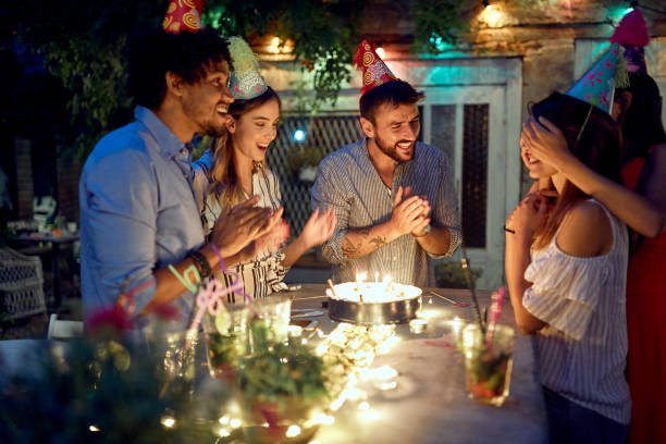 group of cheerful friends surprising a female celebrant at the open air birthday party. quality friendship time together - city night lighting equipment mid air imagens e fotografias de stock