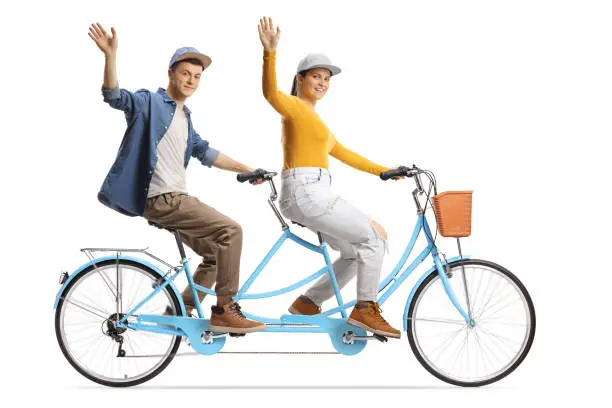 Guy and girl riding a tandem bicycle and waving at camera isolated on white background