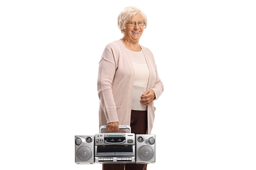 Elderly woman smiling and holding a boombox radio isolated on white background