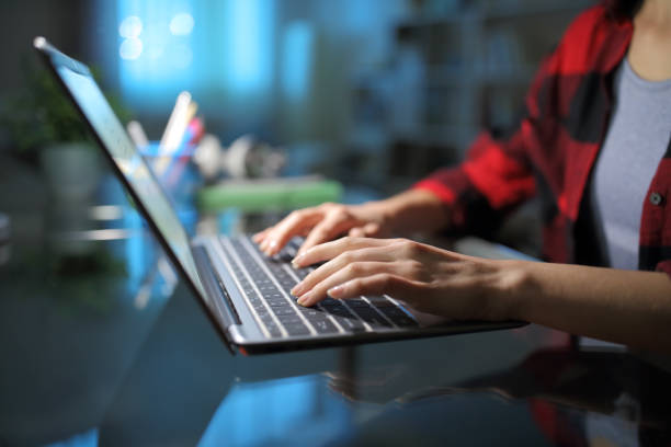 Student hands typing on laptop in the night stock photo