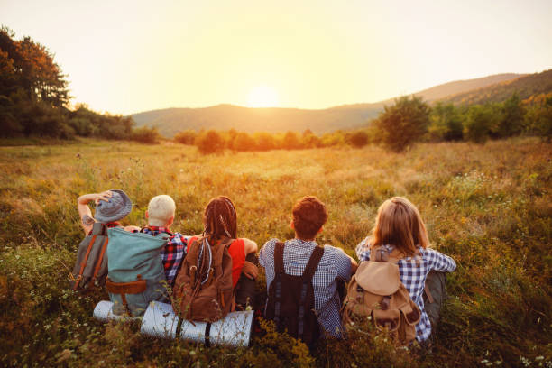 istock Hikers sitting on the field and enjoying the sunset 1318461281