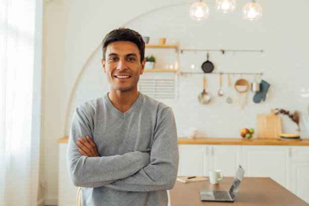 Portrait of smart smiling Caucasian man standing with arms folded at home posing for photos with copy space stock photo