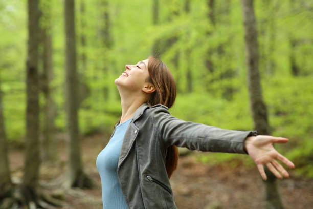 donna felice che si diffonde in una foresta verde - donna profilo braccia alzate foto e immagini stock