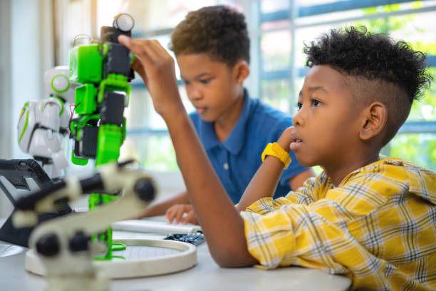 le garçon afro-américain placent le kit de robot dans la salle de classe dans la salle de classe. - computer lab child internet development photos et images de collection