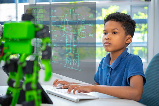 An african american boy use computer program robot kit in class room.