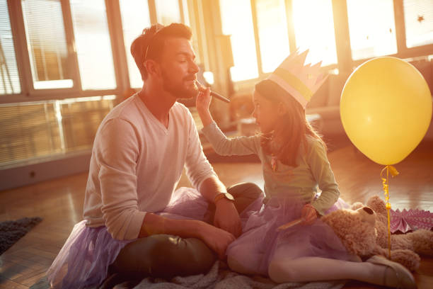 istock A little daughter puts makeup on her father's face while they preparing for ballet exercises at home. Family, together, home 1318464212