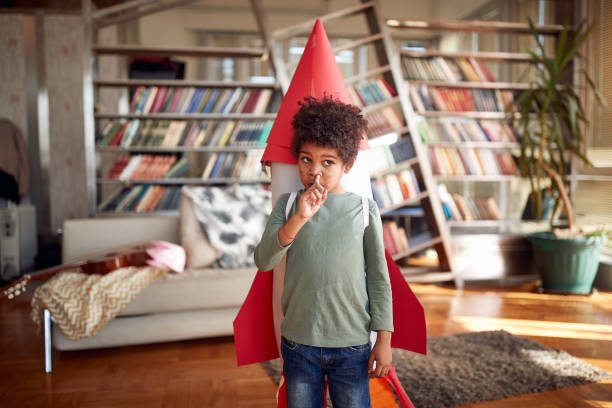 istock A little boy with a rocket toy on his back digs his nose while playing at home. Home, game, childhood 1318465626