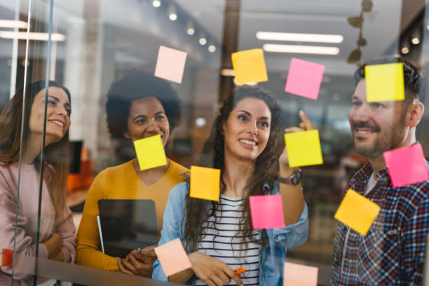 istock Group of web designers using sticky notes on a glass wall during a meeting 1318467151