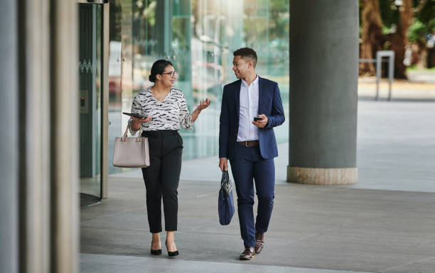 istock Smiling businesspeople talking together while walkiing along a city sidewalk 1318469724