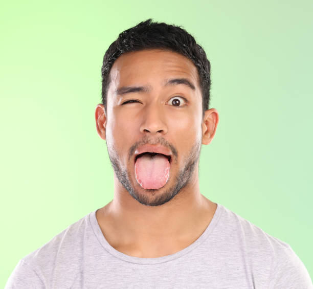 Cropped portrait of a handsome young man making a face against a green background in studio A little quirky young man wink stock pictures, royalty-free photos & images