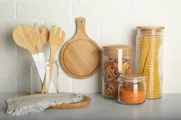 istock Wooden utensils and different products on grey table near white brick wall in kitchen 1318472249