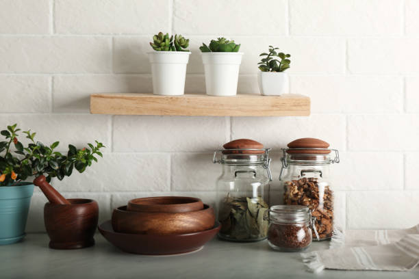 istock Wooden dishware and different products on grey table near white brick wall in kitchen 1318472380