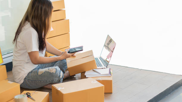 istock Small business owners working with laptops and telephones, mobile and cardboard boxes at work, small business entrepreneurs, SME working with boxes at home, selling online, e-commerce. 1318472680