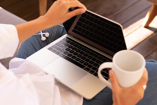 una mujer manos sosteniendo una computadora y una taza de café photo