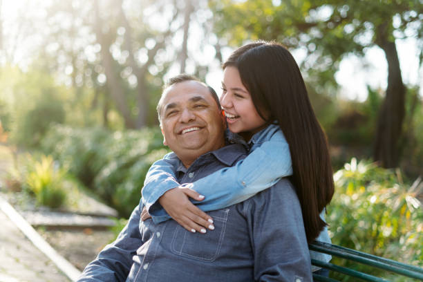 Happy latin father and daughter enjoying time at park stock photo