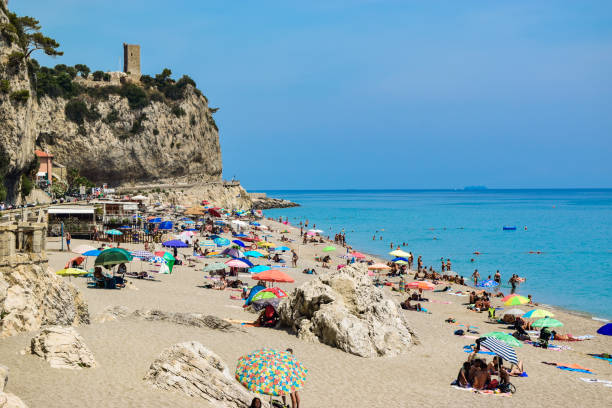 Vacationers on the free sandy and pebble Capo San Donato or Castelleto Pier Beach on a summer, sunny day near the calm Mediterranean Sea. Finale Ligure, Italy - 22 july 2019: Vacationers on the free sandy and pebble Capo San Donato or Castelleto Pier Beach on a summer, sunny day near the calm Mediterranean Sea. Ligurian Riviera coast. finale ligure stock pictures, royalty-free photos & images
