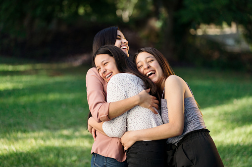 Playful young latin sisters embracing outside and laughing.