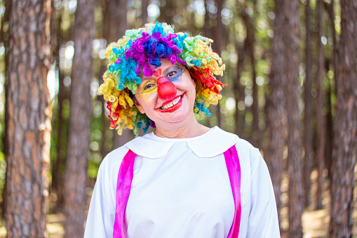 Photo of a woman in clown costume at a tree area.