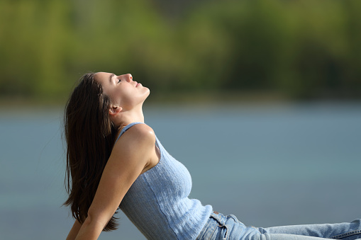 Woman breathing fresh air sitting beside a lake