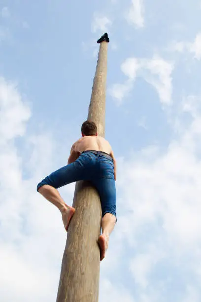 Photo of The man climbs on the pillar. Maslenitsa