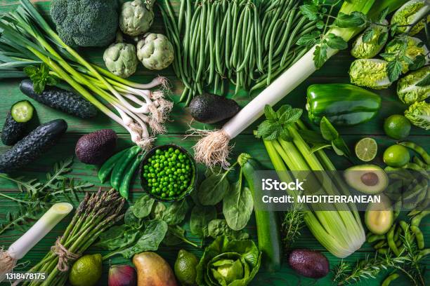 Vegan Raw Vegetables On Green Wooden Table Background Stock Photo - Download Image Now