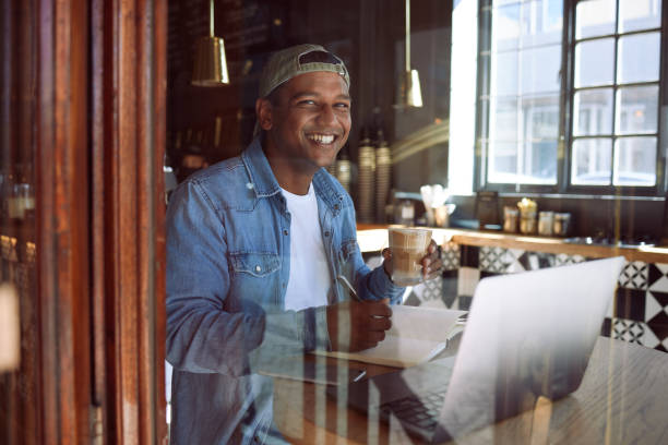 istock Shot of a handsome young man sitting alone in a cafe and making notes while using his laptop 1318481132