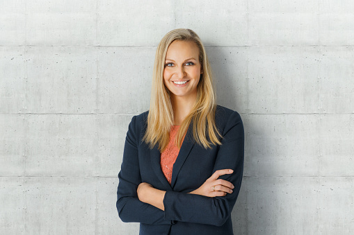 Portrait of a beautiful smiling businesswoman standing with crossed arms in her office and looking at camera.