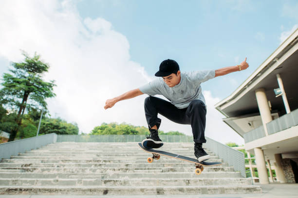 Asian male skateboarder catches some air in a skate park stock photo