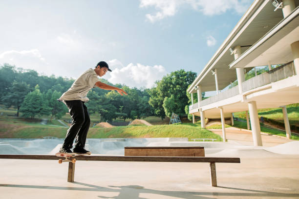 skateboard asiatico maschile in uno skate park - extreme skateboarding action balance motion foto e immagini stock