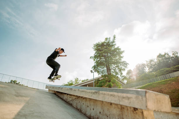 asiatische männliche skateboarder fängt etwas luft in einem skatepark - extreme skateboarding action balance motion stock-fotos und bilder