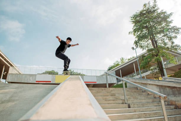 lo skateboarder maschio asiatico prende un po 'd'aria in uno skate park - extreme skateboarding action balance motion foto e immagini stock