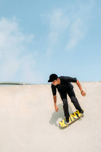 skateboard asiatico maschile in uno skate park - extreme skateboarding action balance motion foto e immagini stock