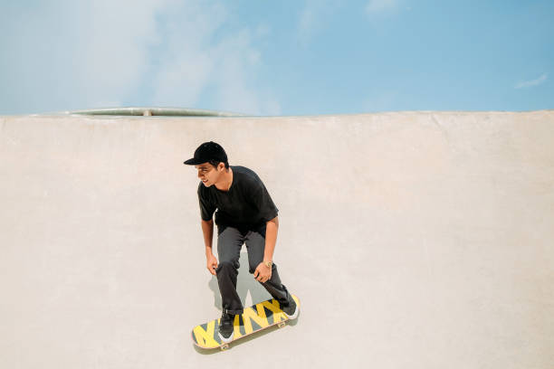 skateboard asiatico maschile in uno skate park - extreme skateboarding action balance motion foto e immagini stock