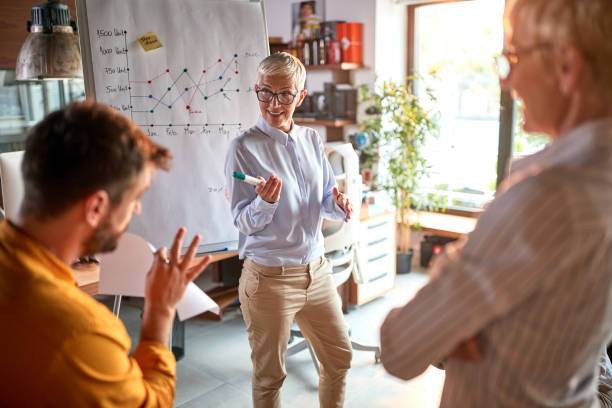 istock An elderly female boss is questioning her young male colleague while holding a presentation at workplace. Business, office, job 1318484041