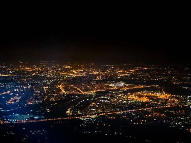 aerial view of illuminated suburbs of Moscow city at night from porthole while flying by plane